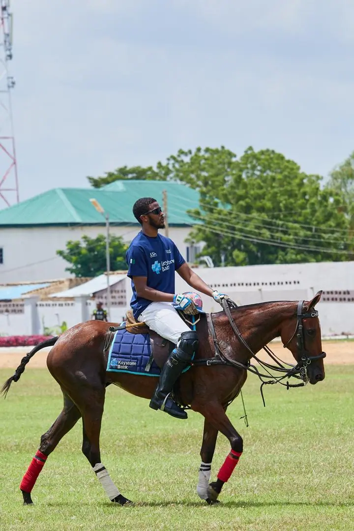 Polo player in a Keystone Bank team jersey riding onto the field before a match