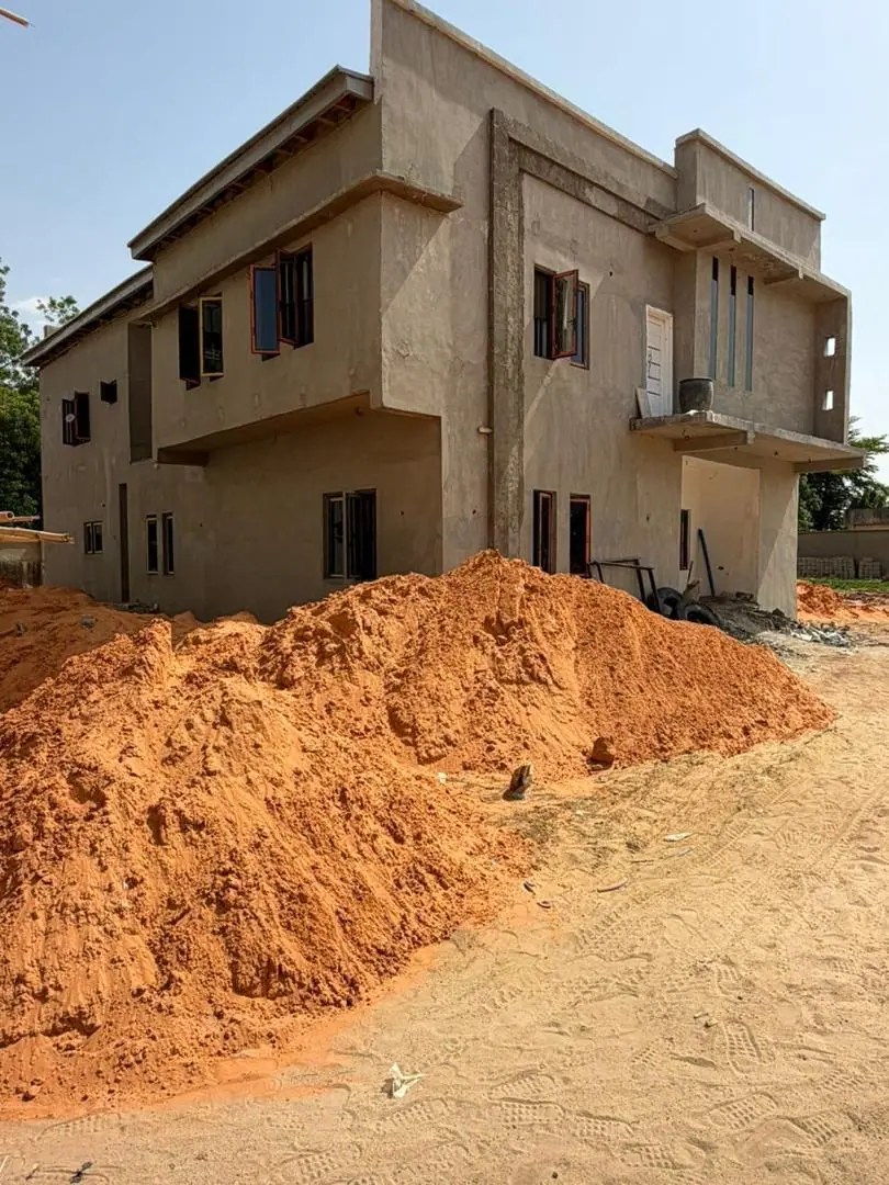 Site photograph of a Three of Us duplex at plastering stage, with window openings formed and earthworks in front